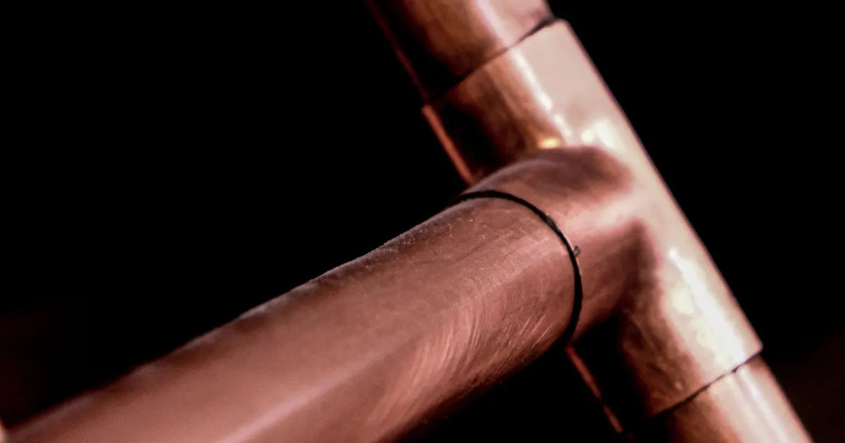 Copper tube fitting against a dark background, an example of copper parts for 5 axis copper machining