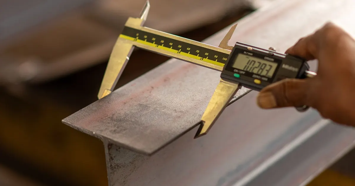 Digital caliper measuring a steel part, as used in 5 axis first article inspection in Vietnam